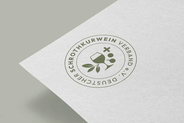 The round seal of the Deutscher Schrothkurwein Verband in olive ink on white card: a wine glass, grapes, an olive sprig and a cross